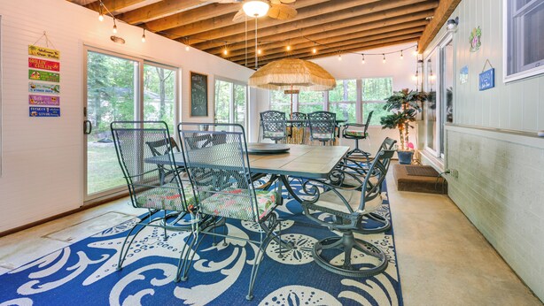 Ein überdachter Patio-Bereich mit Metallstühlen, einem Tisch und einem Deckenventilator.