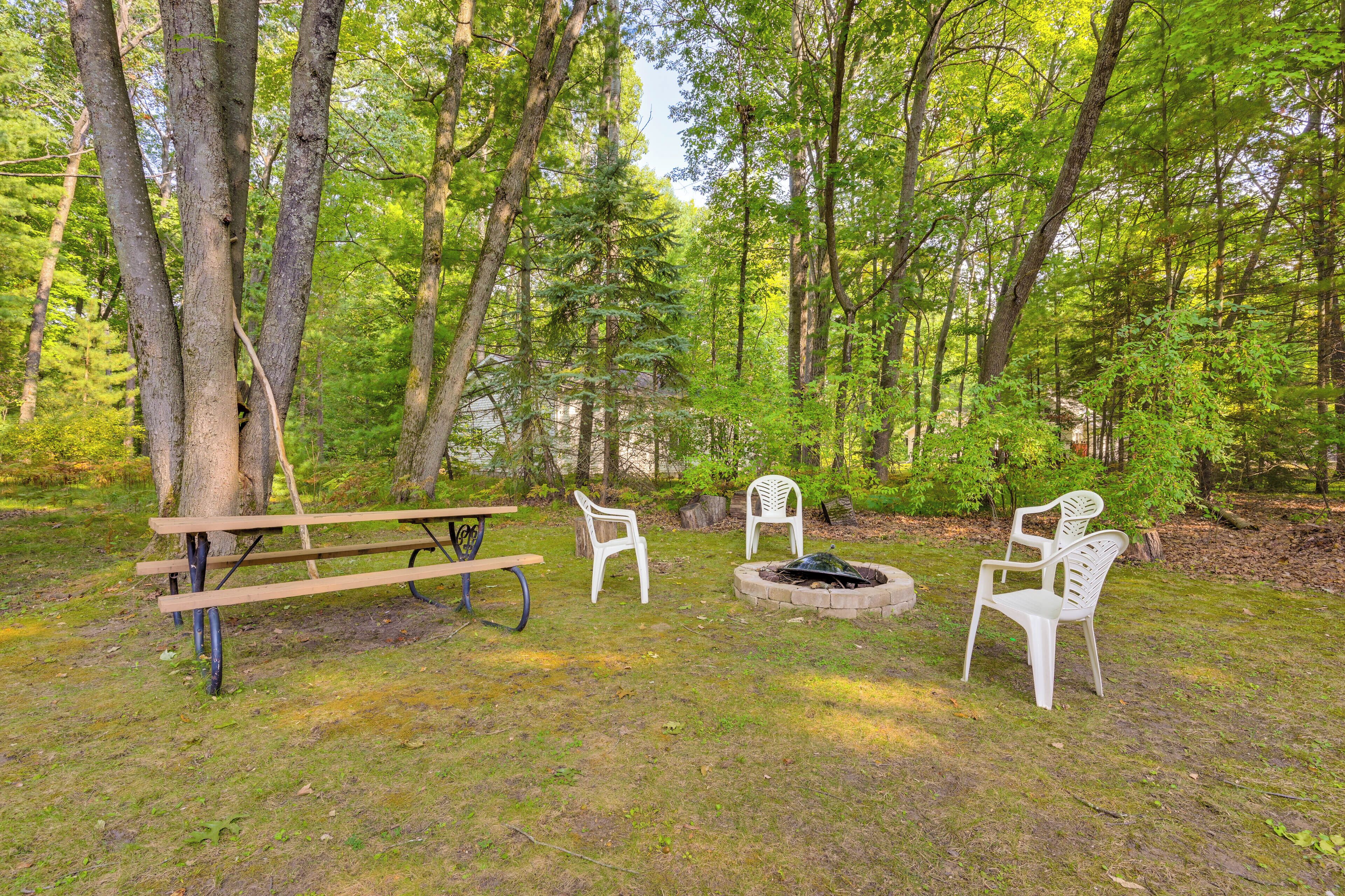 Un espace pique-nique avec une table et des chaises en bois, entouré d’arbres.