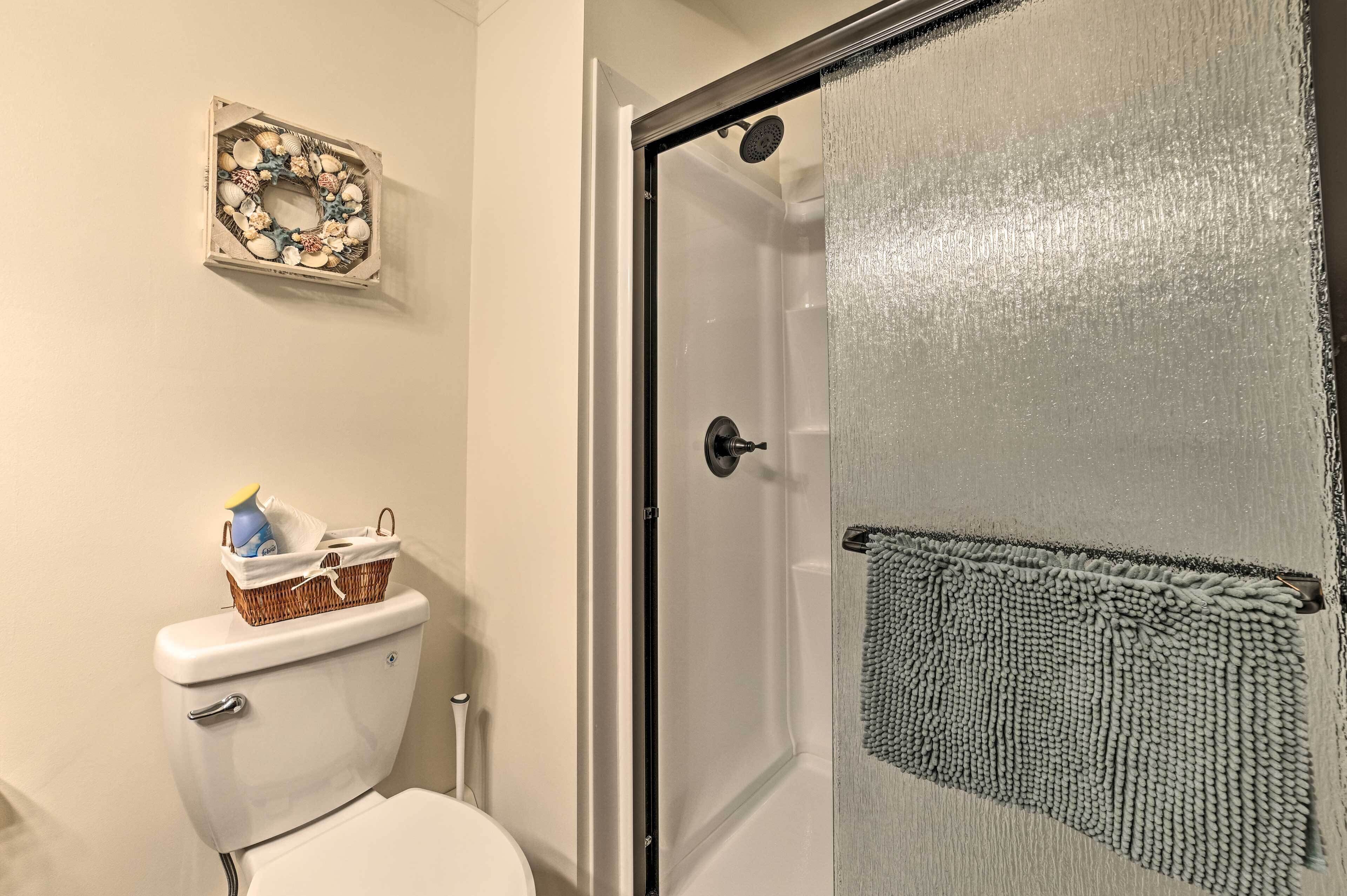 A bathroom with a shower, toilet, and a decorative wreath on the wall.