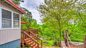 A wooden staircase leading to a porch with a red roof, surrounded by lush greenery and trees. - Cozy Kentucky Cabin w/ Sunroom, Yard & Views! (Cub Run)