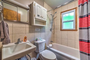 A bathroom with a sink, toilet, bathtub, and a window with a view.