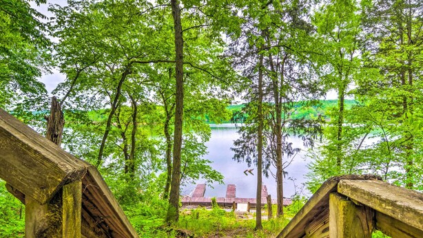 A wooden staircase leading to a dock over a lake, surrounded by lush green trees. - Cozy Kentucky Cabin w/ Sunroom, Yard & Views! (Cub Run)