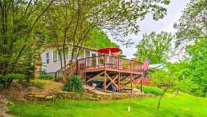 A two-story house with a deck and an American flag. - Cozy Kentucky Cabin w/ Sunroom, Yard & Views! (Cub Run)
