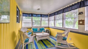 A sunroom with yellow walls, wicker furniture, and a patterned rug. - Cozy Kentucky Cabin w/ Sunroom, Yard & Views! (Cub Run)