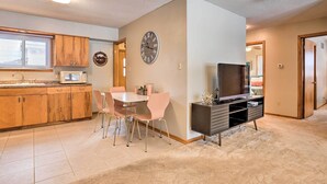 Una cocina moderna con armarios de madera, un microondas y un comedor con mesa y sillas.