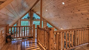 A wooden interior with a sloped ceiling, wooden railings, and a view of greenery outside. - 'camp Tony' w/ Trail Access: Walk to Lake Huron! (Millersburg)