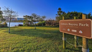 A sign for Cotton Bayou Park with a grassy area and trees in the background. - 1 Mi to Beach Access: Spacious Orange Beach Duplex (Orange Beach)