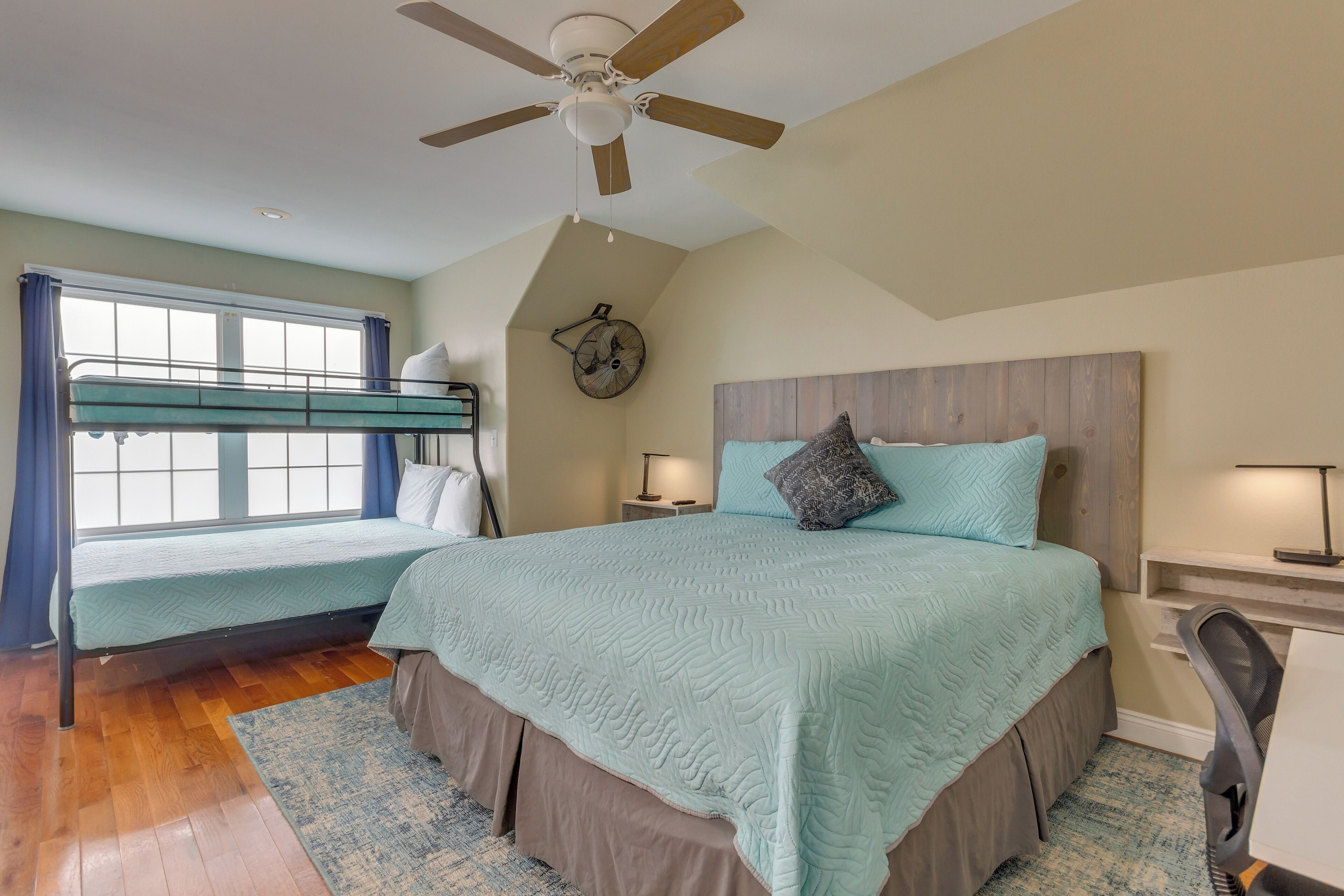 A bedroom with a bunk bed, a desk, a chair, a ceiling fan, and a clock on the wall.