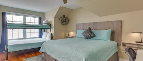 A bedroom with a bunk bed, a desk, a chair, a ceiling fan, and a clock on the wall.