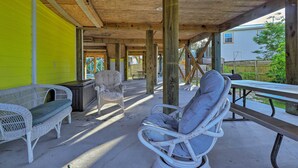 An outdoor covered patio with wicker furniture, a picnic table, and a wooden ceiling structure. - 1 Mi to Beach Access: Spacious Orange Beach Duplex (Orange Beach)