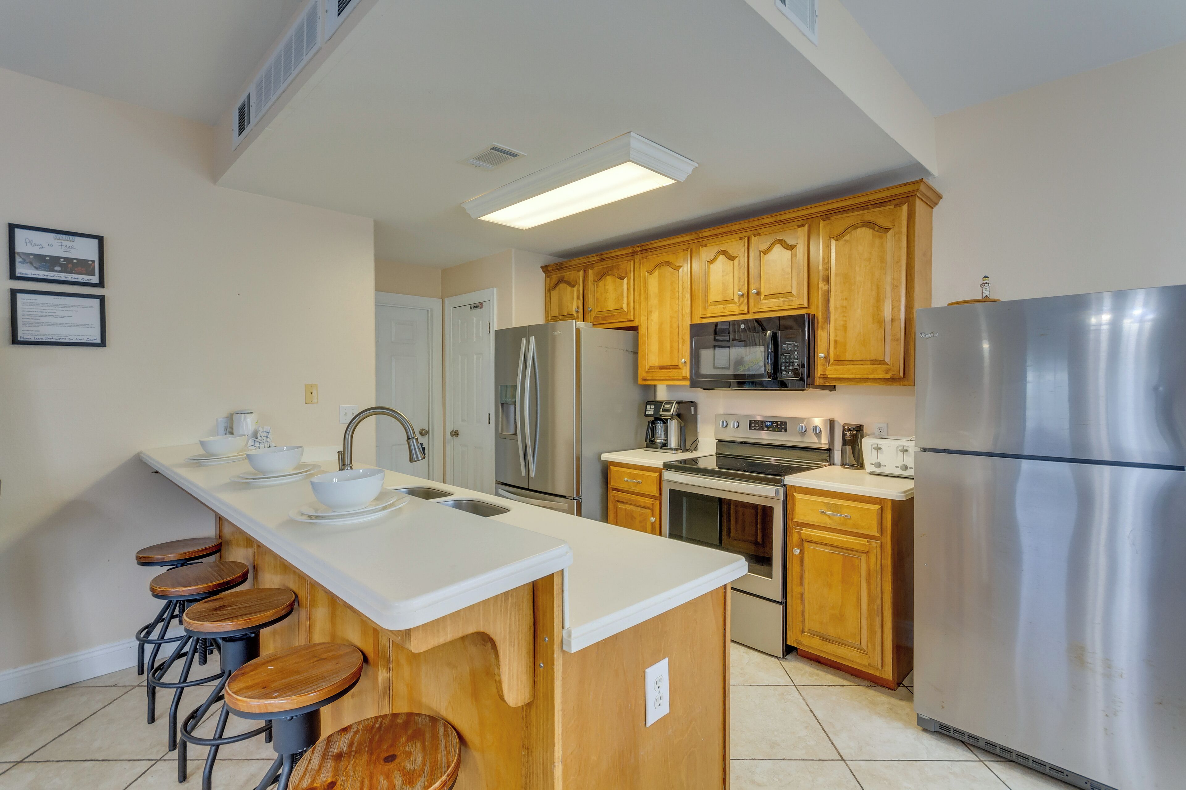 A modern kitchen with wooden cabinets, stainless steel appliances, and a white countertop.