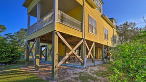 A two-story yellow house with a balcony, wooden support beams, and a picnic table in the yard. - 1 Mi to Beach Access: Spacious Orange Beach Duplex (Orange Beach)