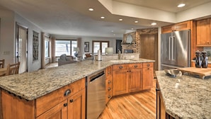 A spacious kitchen with granite countertops, wooden cabinets, and a stainless steel refrigerator. - Charming Joliet Ranch House on a Working Farm (Joliet)