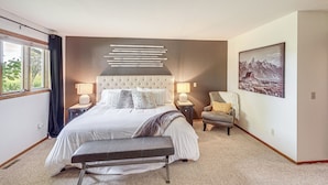 A bedroom with a large bed, bedside tables, a bench, a chair, a painting, and a window with curtains. - Charming Joliet Ranch House on a Working Farm (Joliet)