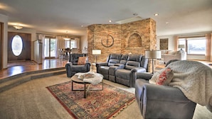 A spacious living room with a brick accent wall, leather sofas, and a large rug. - Charming Joliet Ranch House on a Working Farm (Joliet)