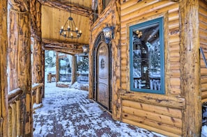 Eine Holzhütte mit einer verschneiten Veranda und einer großen Holztür.