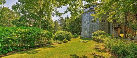 A stone tower surrounded by lush greenery and a well-maintained lawn.