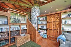 A cozy room with wooden bookshelves, a stone pillar, and a staircase leading to a loft area.