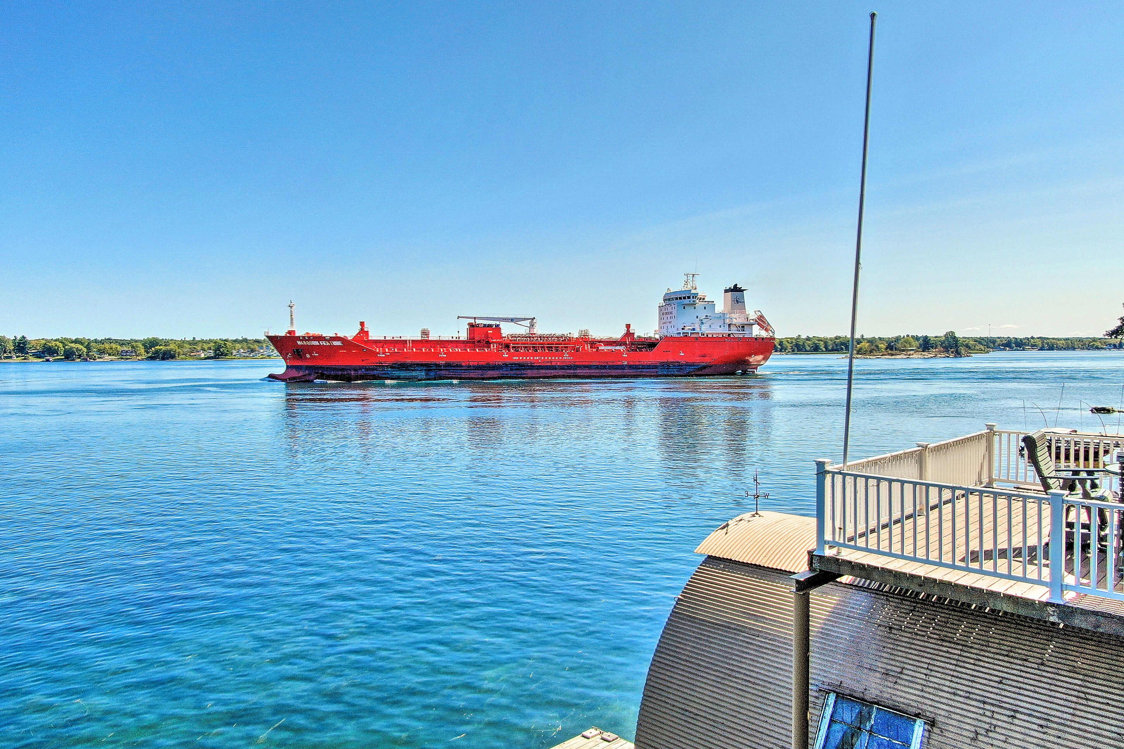 A large red cargo ship on a calm body of water.