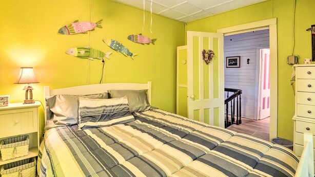 Ein Schlafzimmer mit Bett, Nachttisch, Kommode und einer Tür zu einem weiteren Raum.