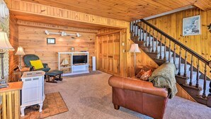Ein gemütliches Wohnzimmer mit Holzwänden, einem Kamin, einem Fernseher und einer Treppe.