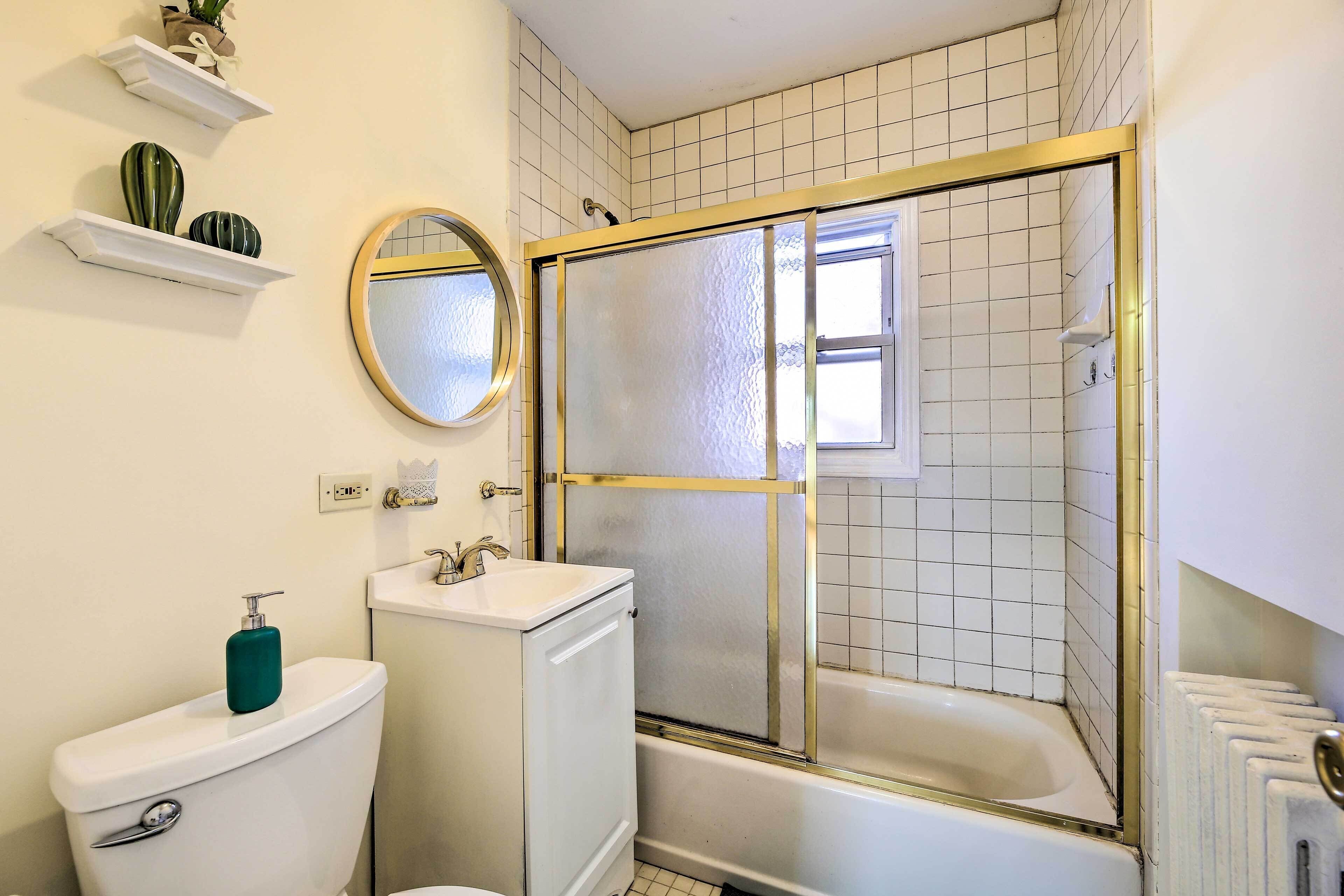 Ein Badezimmer mit Toilette, Waschbecken, Spiegel, Duschkabine und gefliesten Wänden.