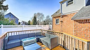 A covered patio with wicker furniture and a wooden deck.