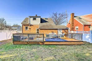 A two-story house with a backyard deck, a patio with outdoor furniture, and a brick chimney.