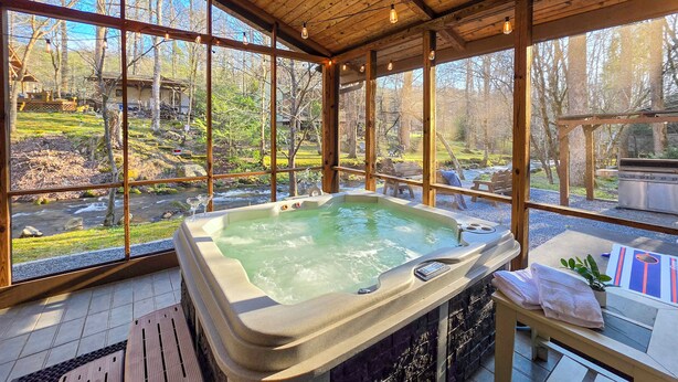 Un jacuzzi en una habitación de madera con ventanas amplias que dan a un paisaje natural.