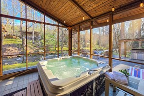 Ein Whirlpool in einem Holzraum mit großen Fenstern, die eine natürliche Landschaft zeigen.
