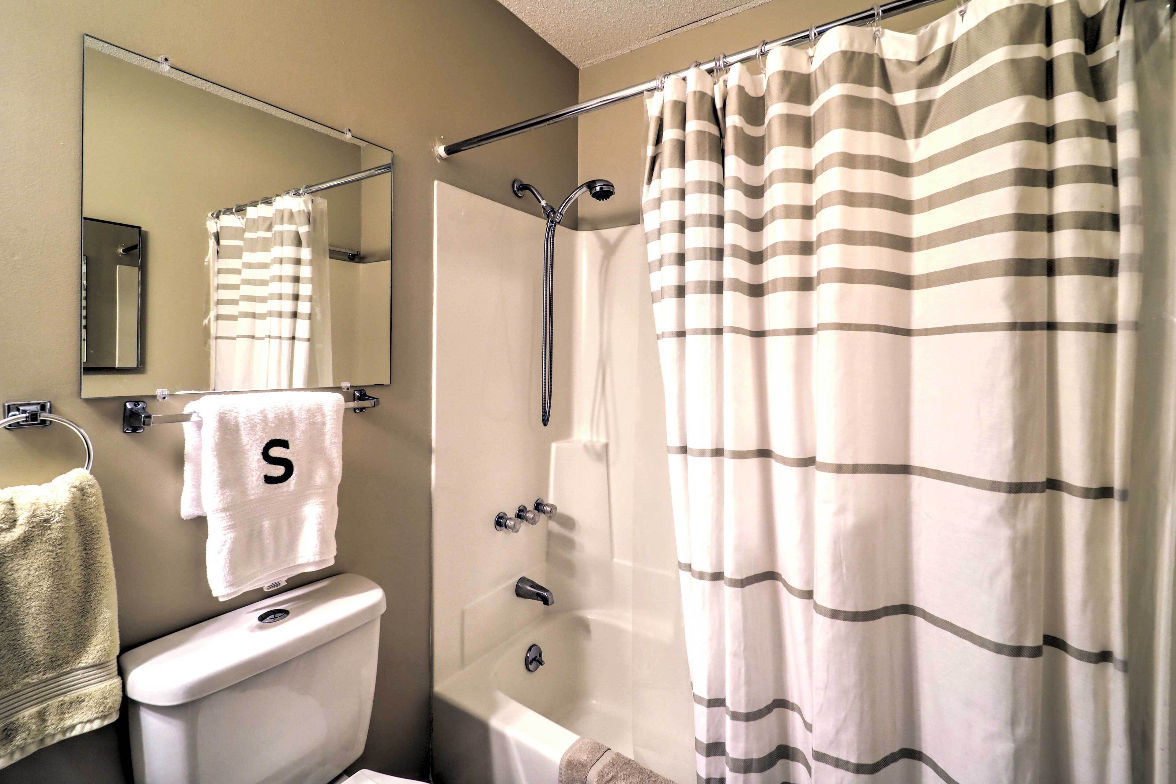 A bathroom with a shower, toilet, and a mirror.
