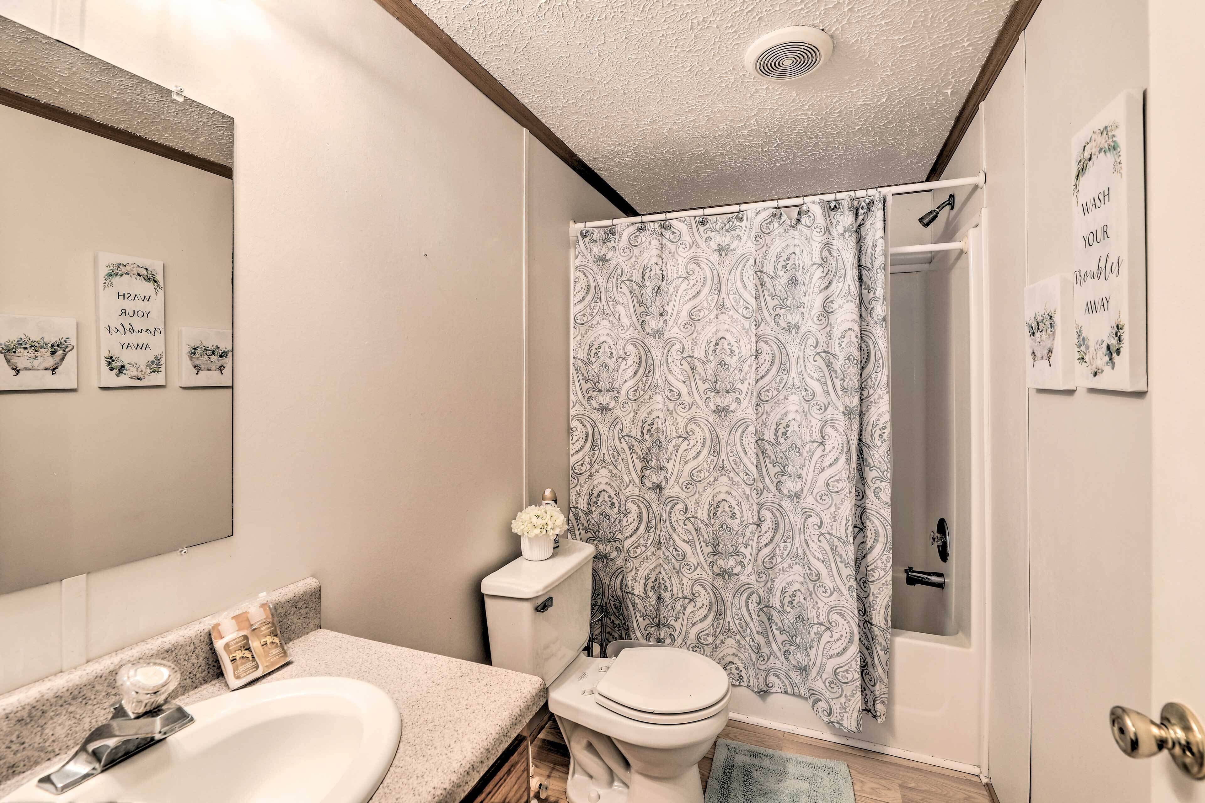 Une salle de bain équipée de toilettes, d’un lavabo, d’un rideau de douche et d’un miroir.