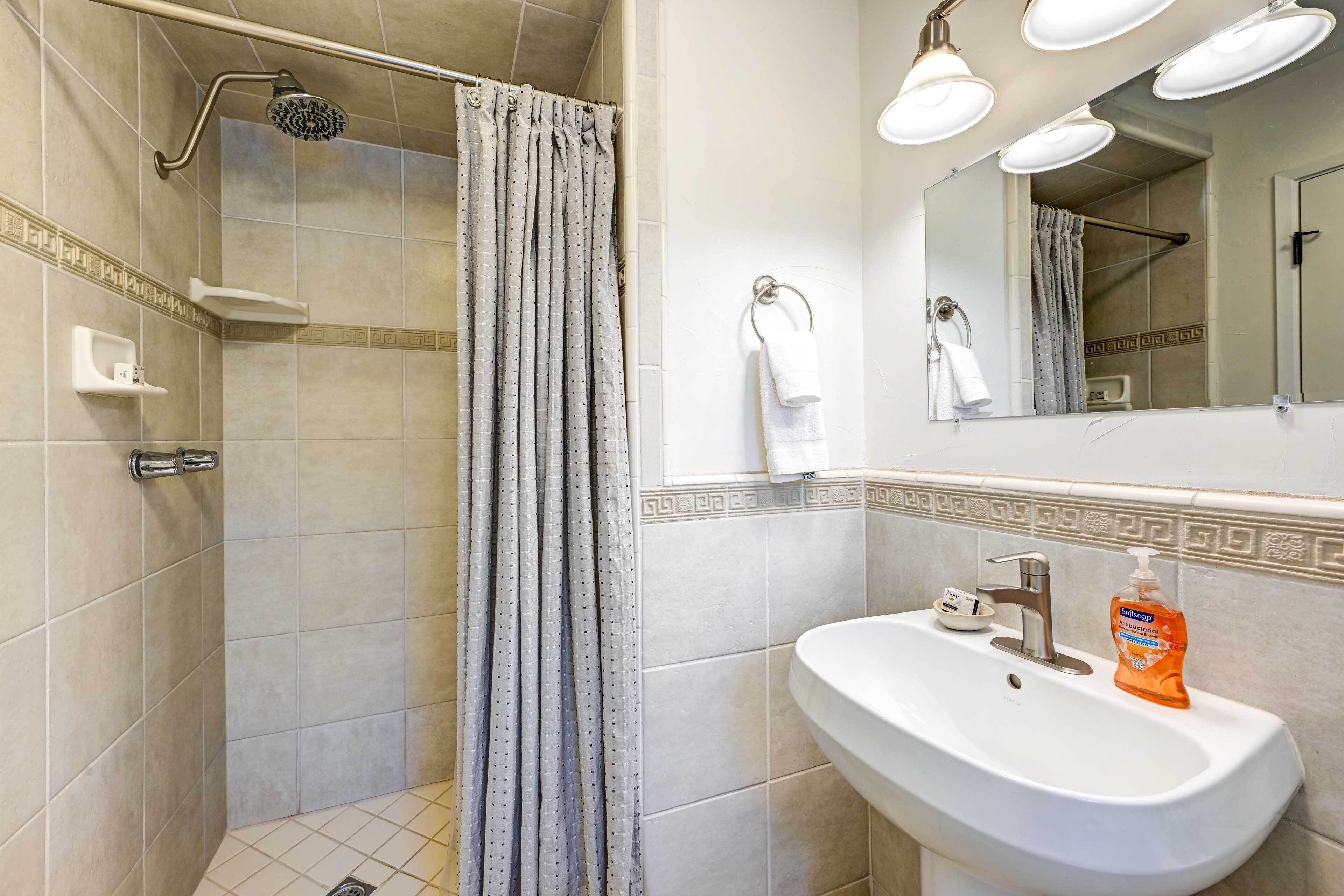 Ein Badezimmer mit Dusche, Waschbecken, Spiegel und Handtuchhalter.