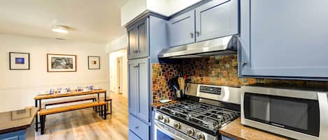 Una cocina con armarios azules, estufa a gas y microondas.