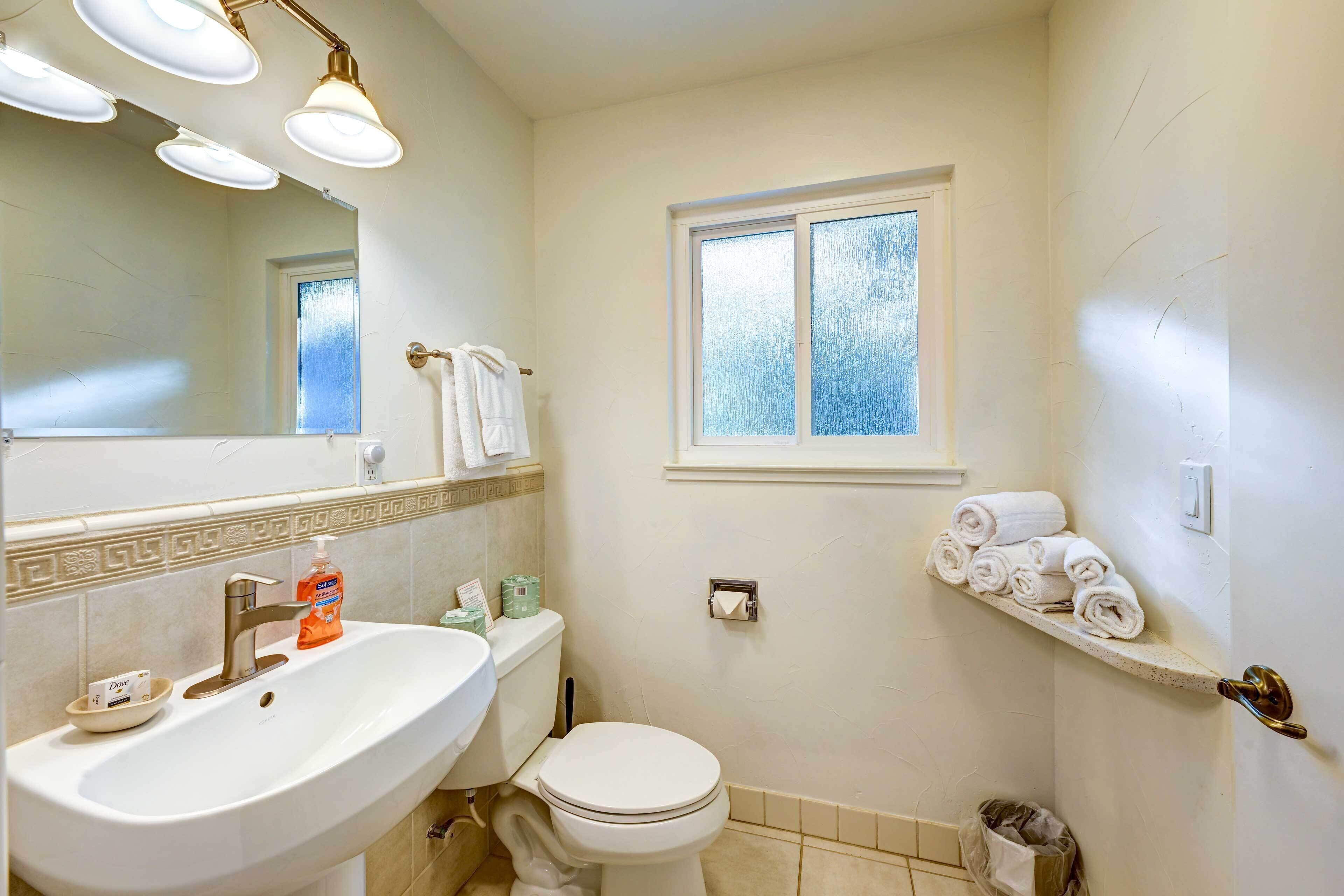 A bathroom with a sink, toilet, and a window.