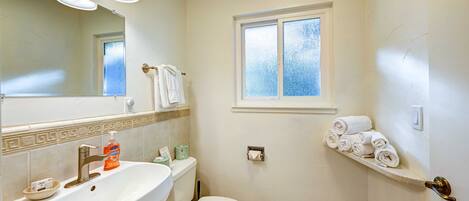 A bathroom with a sink, toilet, and a window.