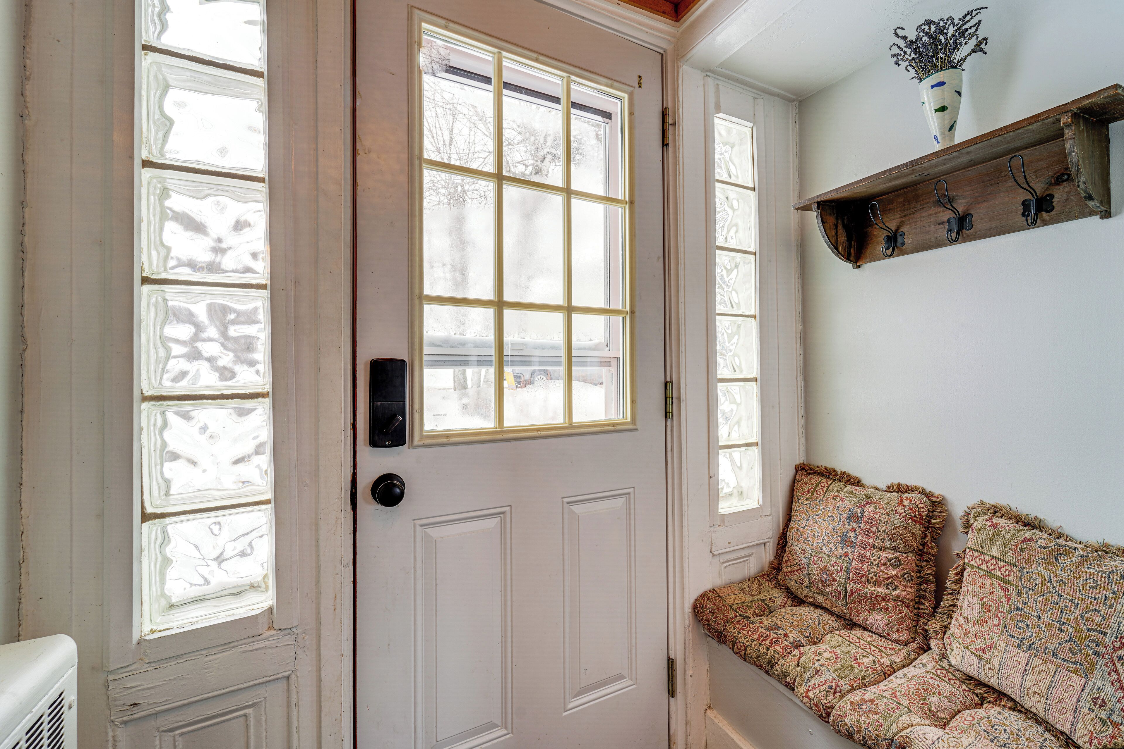 A white door with frosted glass panels and a bench with patterned cushions.