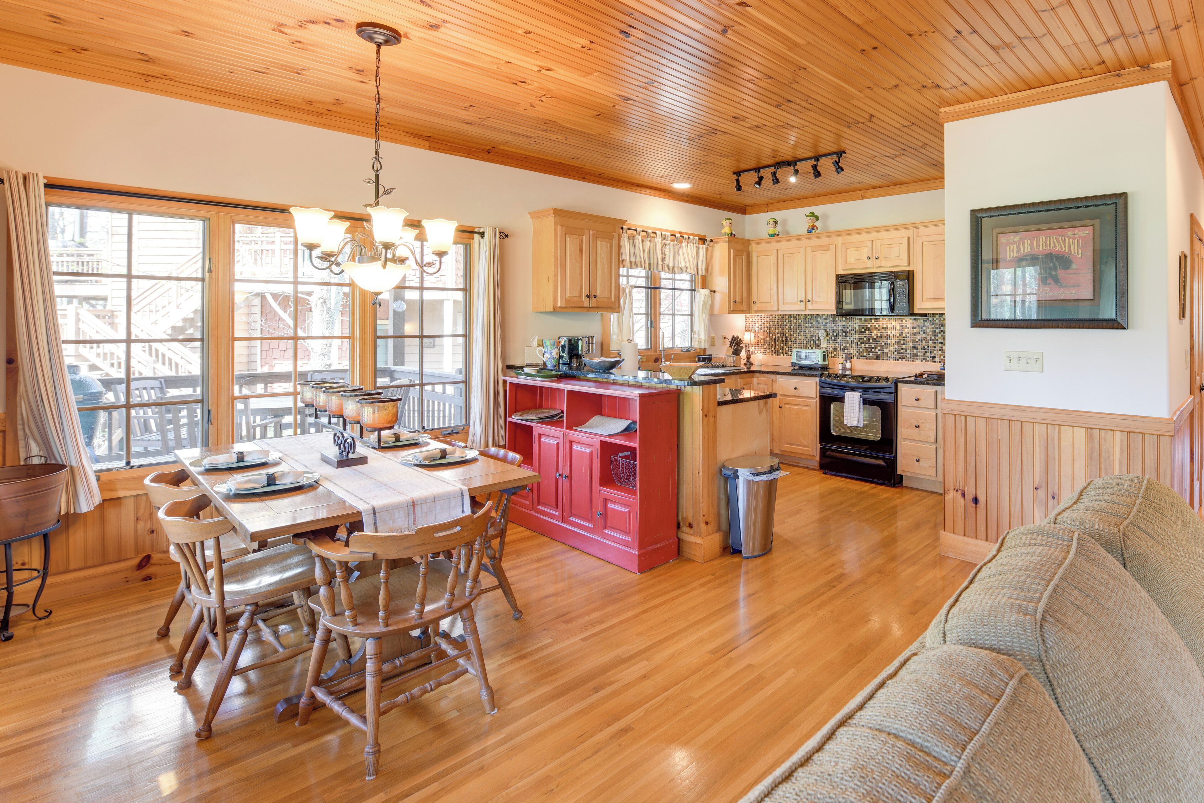 A spacious kitchen with wooden cabinets, a central island, and a dining area with wooden chairs.