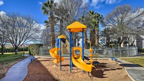A playground with a slide and climbing structures, surrounded by sand and trees. - Beautiful St George Condo ~ 5 Mi to Downtown! (St. George)