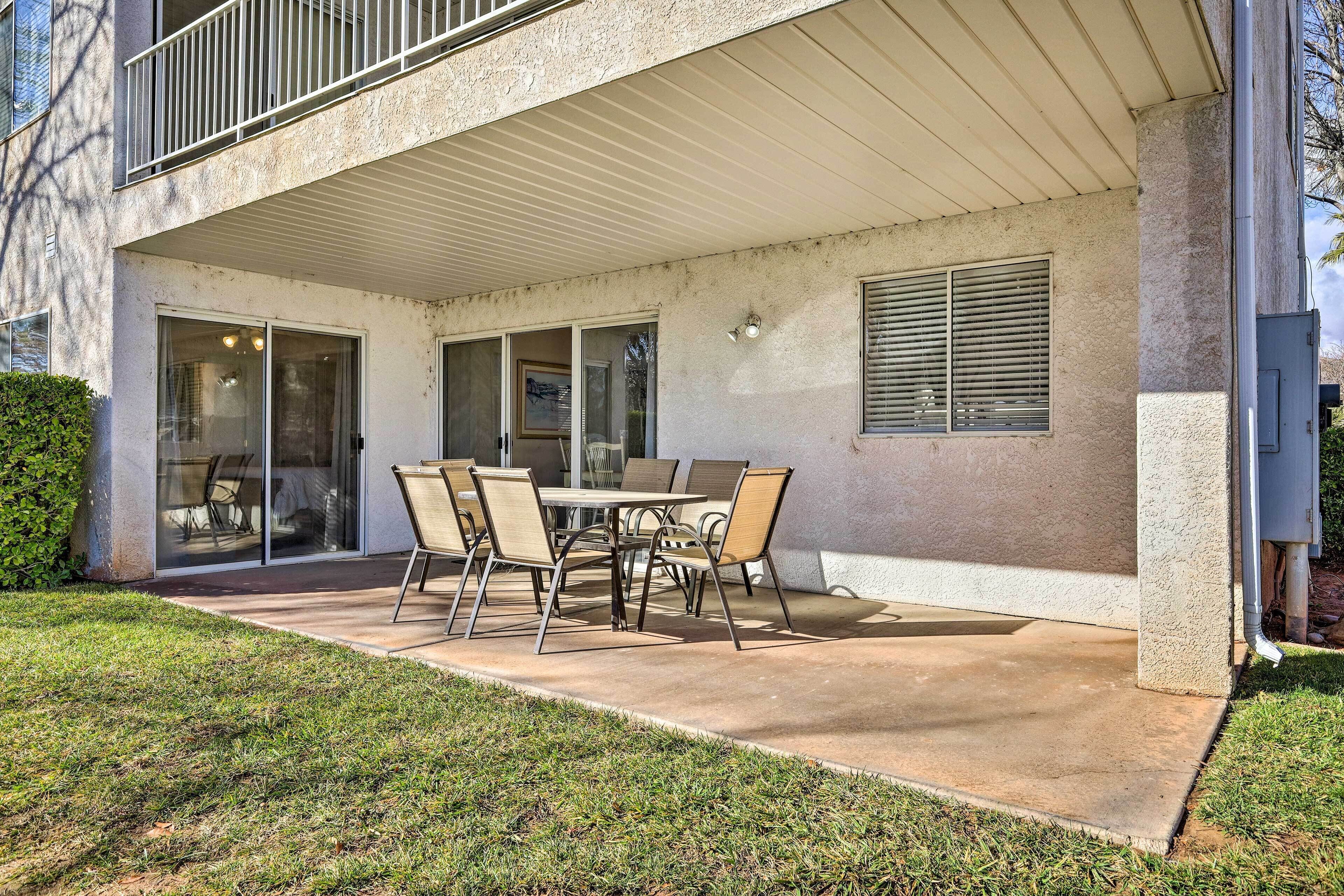 Une terrasse couverte avec une table et des chaises, une porte-fenêtre coulissante et une fenêtre avec des stores.