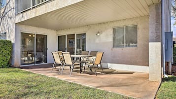 A covered patio with a table and chairs, a sliding glass door, and a window with blinds.