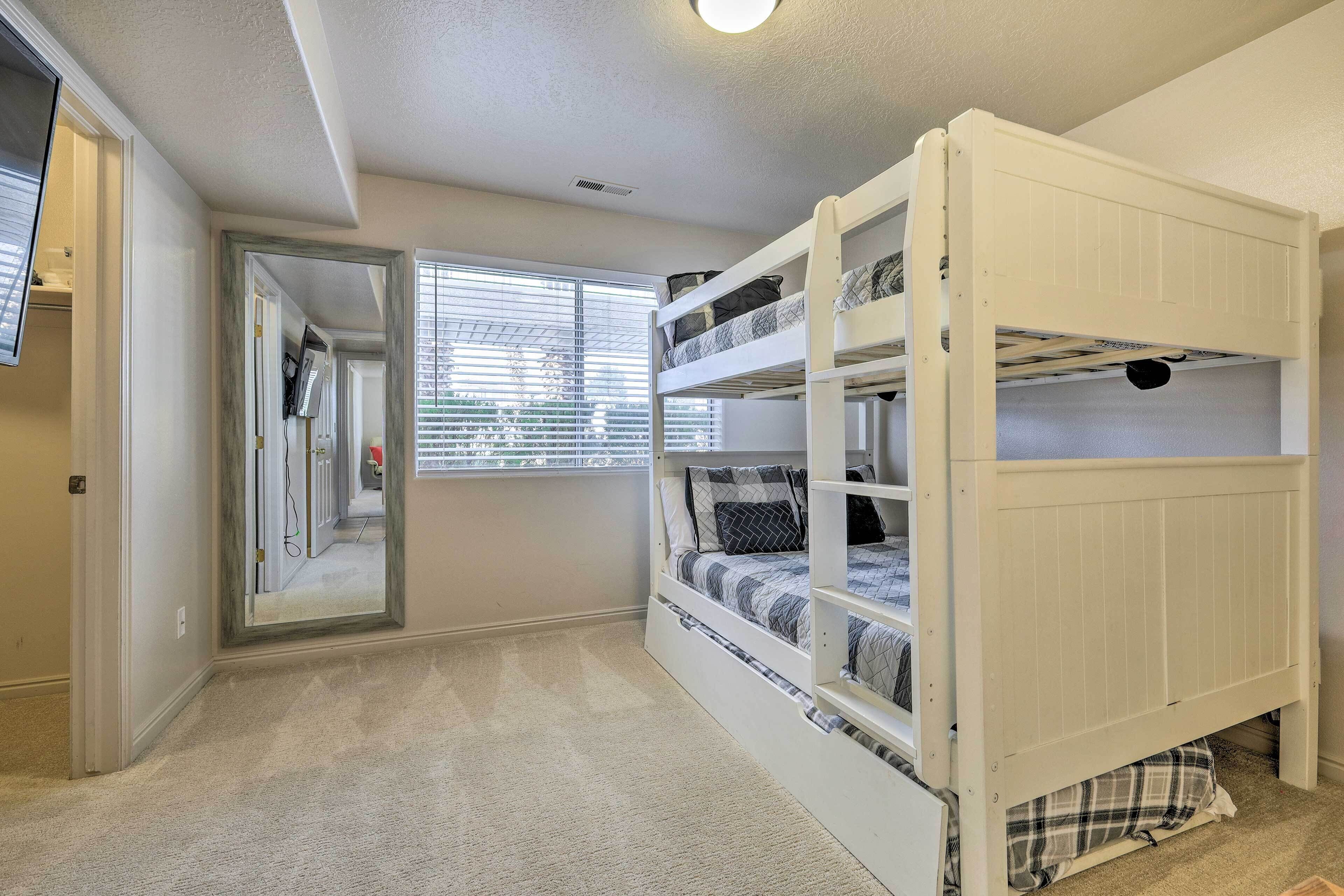 A room with a bunk bed, a mirror, and a window with blinds.