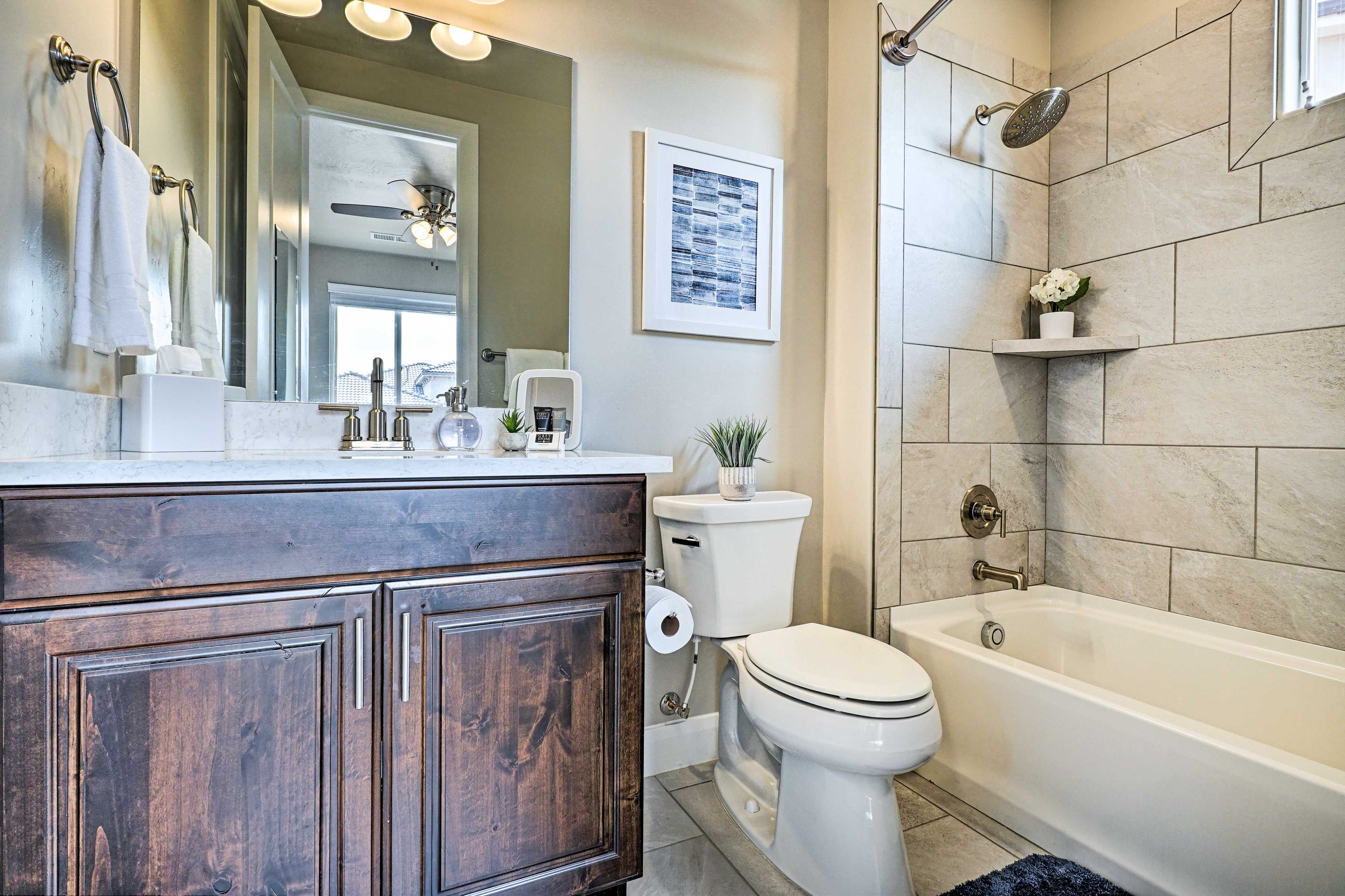 A bathroom with a dark wood vanity, white toilet, and a bathtub.