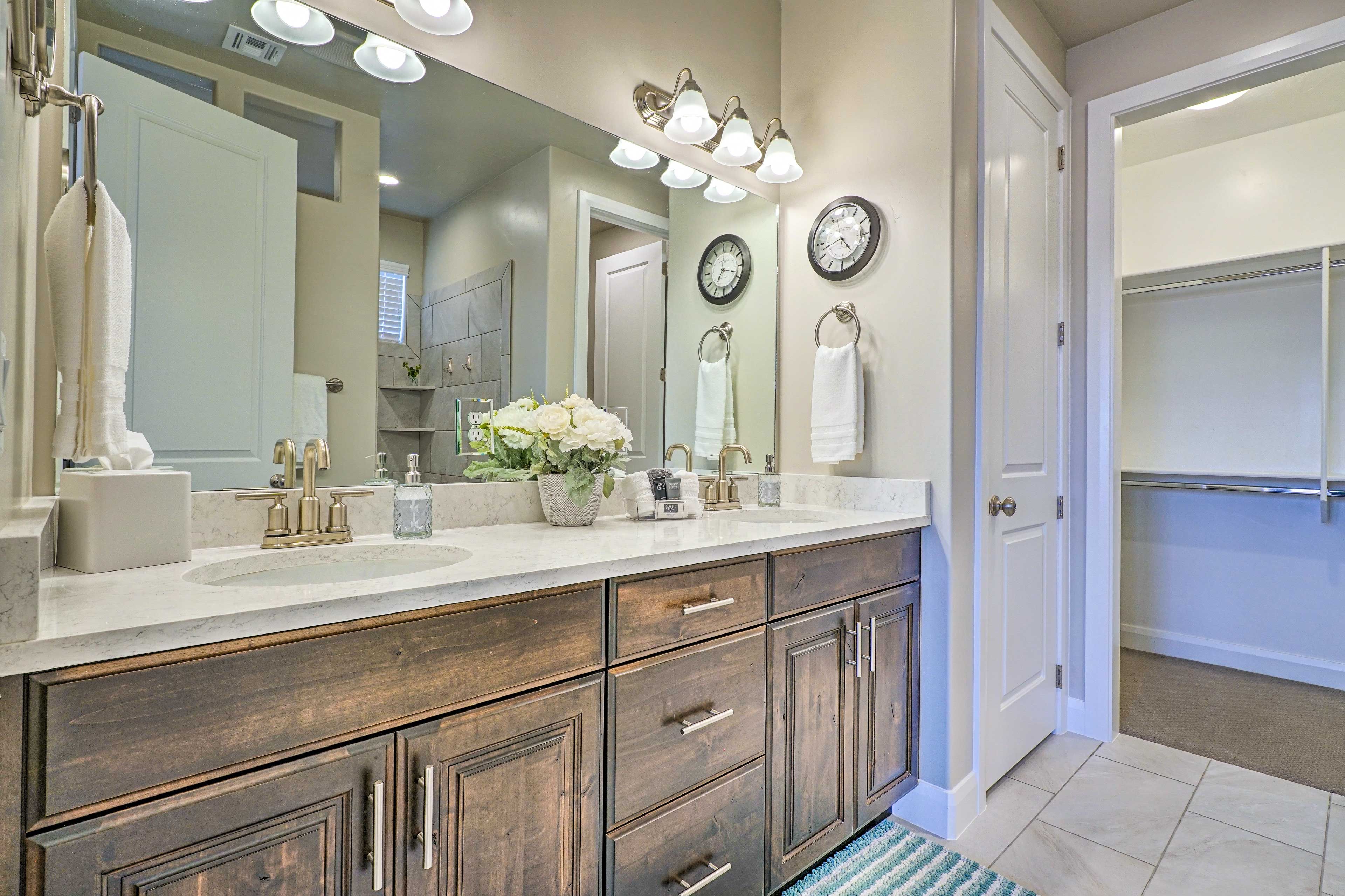 A bathroom with a large mirror, vanity with a sink, multiple drawers, and a towel rack.