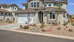 A two-story house with a stone facade, a garage, and a landscaped front yard with rocks and sparse vegetation. - Utah Group Getaway w/ Patio! Swim, Soak & Hike (Washington)