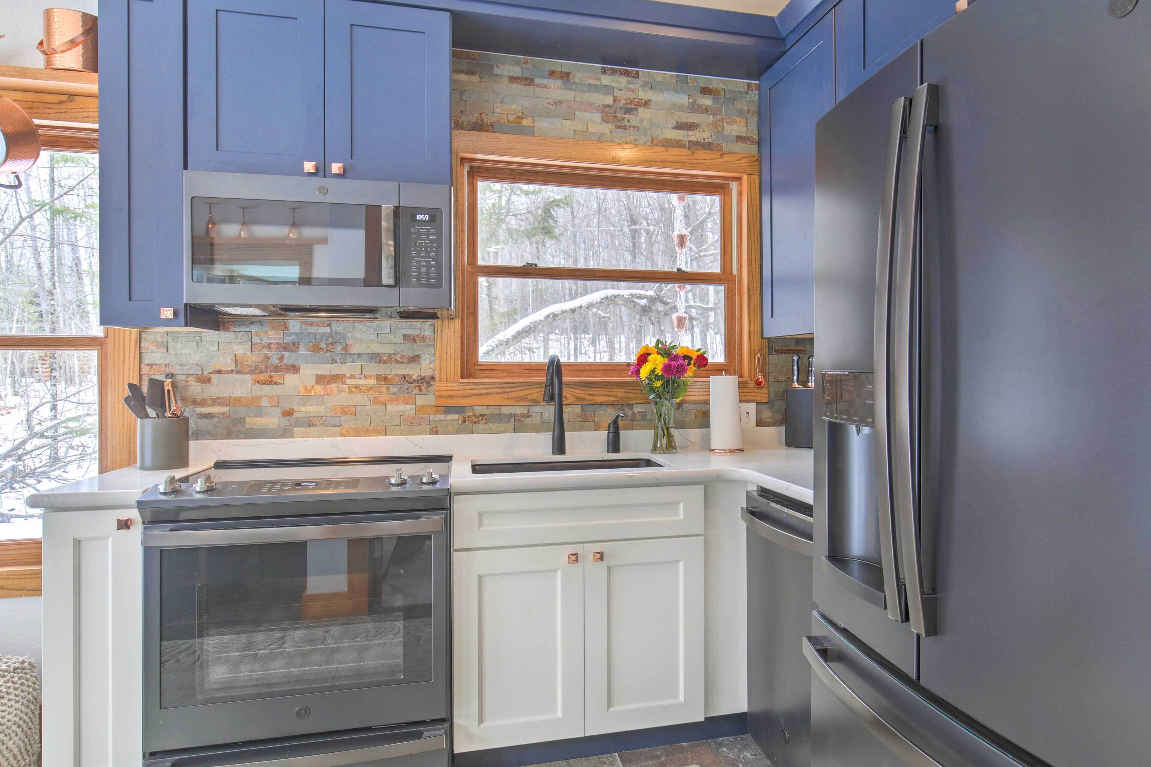 A modern kitchen with a stainless steel refrigerator, built-in oven, and microwave.