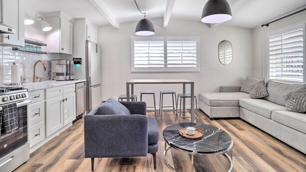 Une cuisine moderne avec des meubles blancs, une cuisinière et un coin repas comprenant une table et des chaises.
