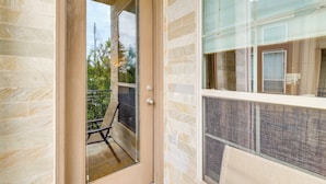 A modern building with a glass door leading to a balcony with a chair.