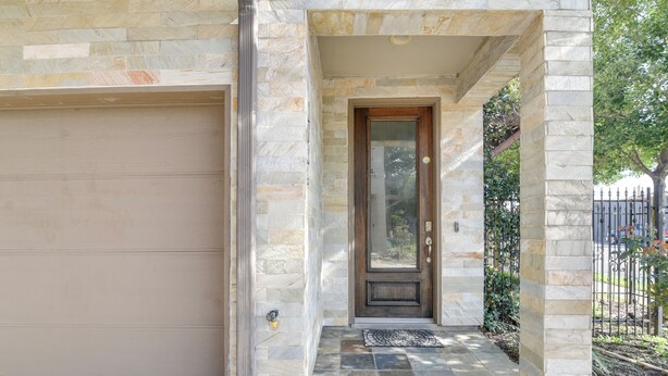 A stone exterior with a garage door, a wooden door, and a stone-paved entrance.