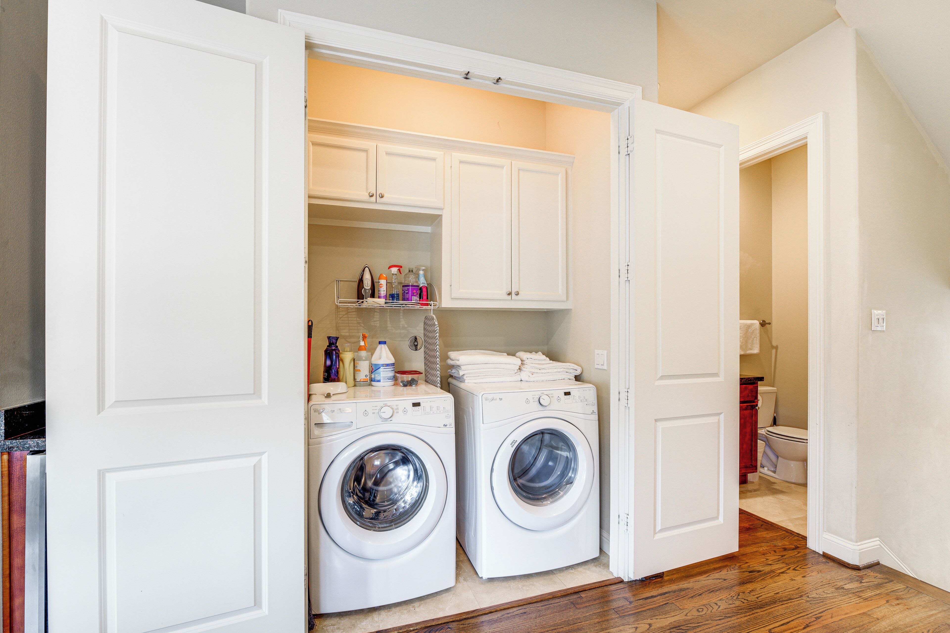 A laundry room with two washing machines, a shelf with cleaning supplies, and a small storage area.